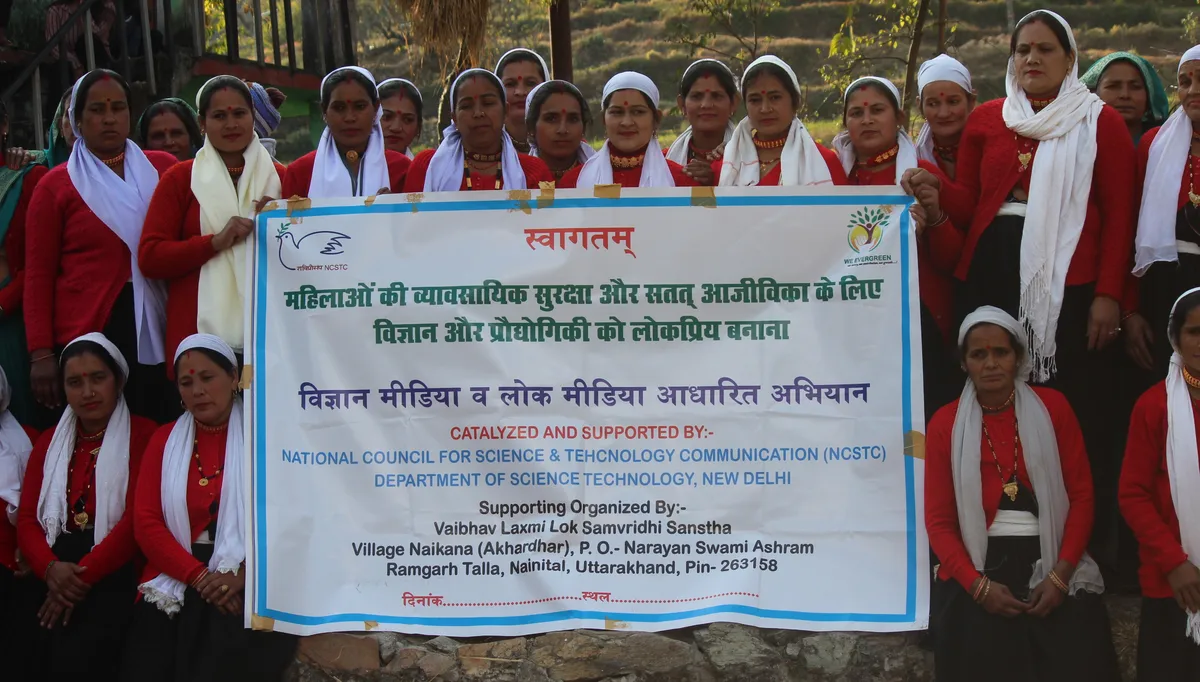 Women gather behind a programme banner about occupational security and sustainable livelihoods.