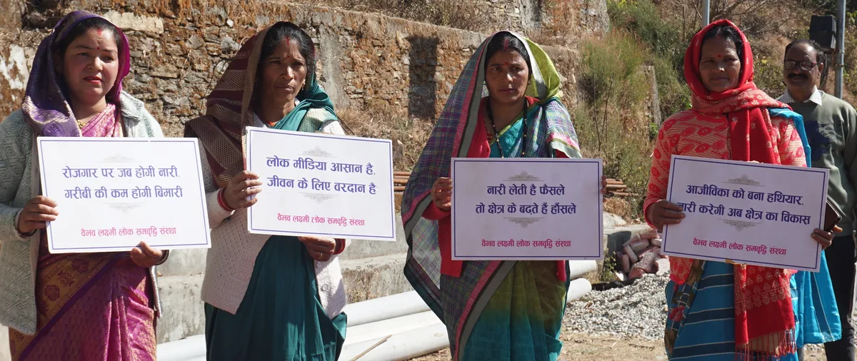 Women hold placards about livelihoods, folk media, and women’s participation at Kaflodi.