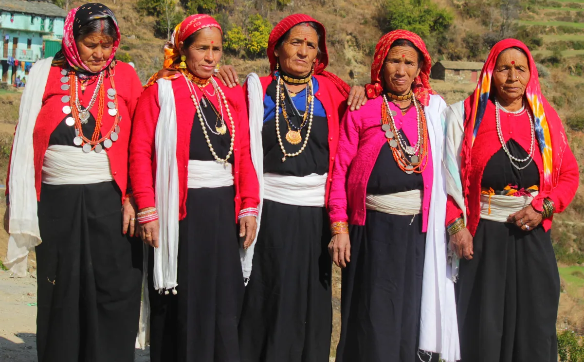 Women in traditional clothing and jewellery pose outdoors at a cultural gathering.